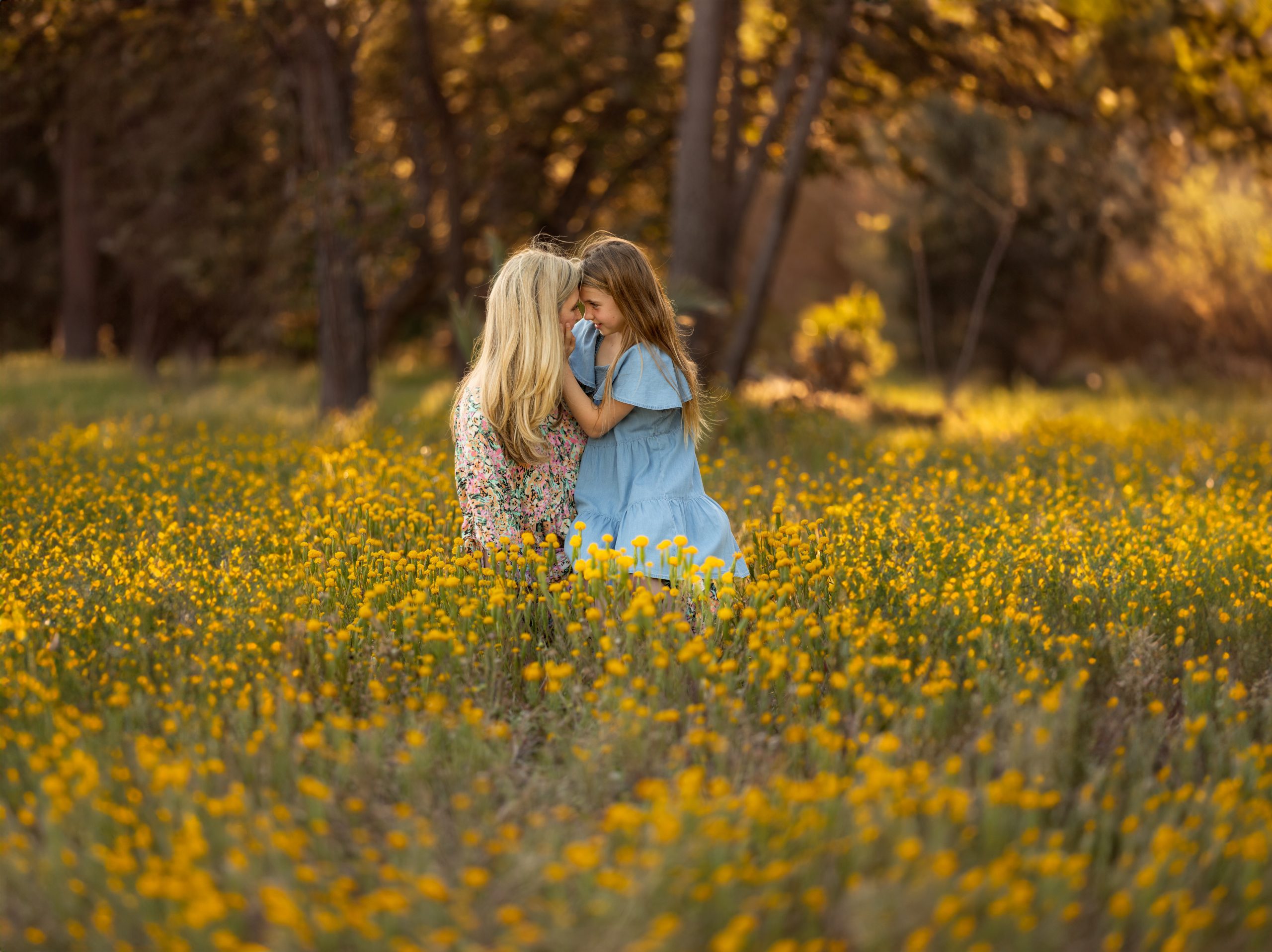 mother and daughter sitting in a field of flowers